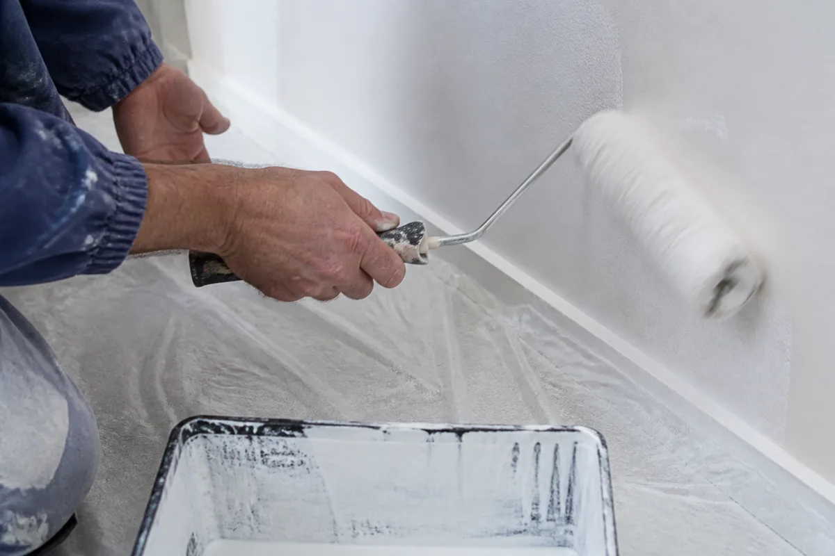 Artisan appliquant une finition de peinture sur un mur intérieur