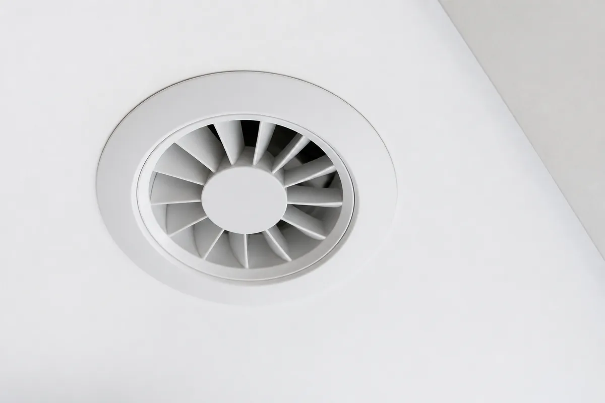 Bouche d’extraction de ventilation mécanique dans un plafond blanc récemment rénové